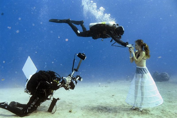 A model opens her mouth to breathe from a scuba tank during an underwater photo shoot in Eilat