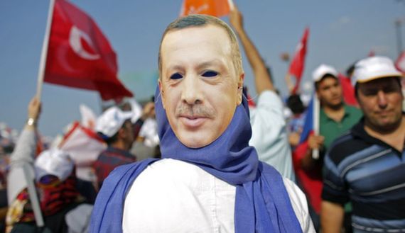 A supporter wears a mask showing Turkish PM Erdogan during a rally of ruling AK party in Istanbul