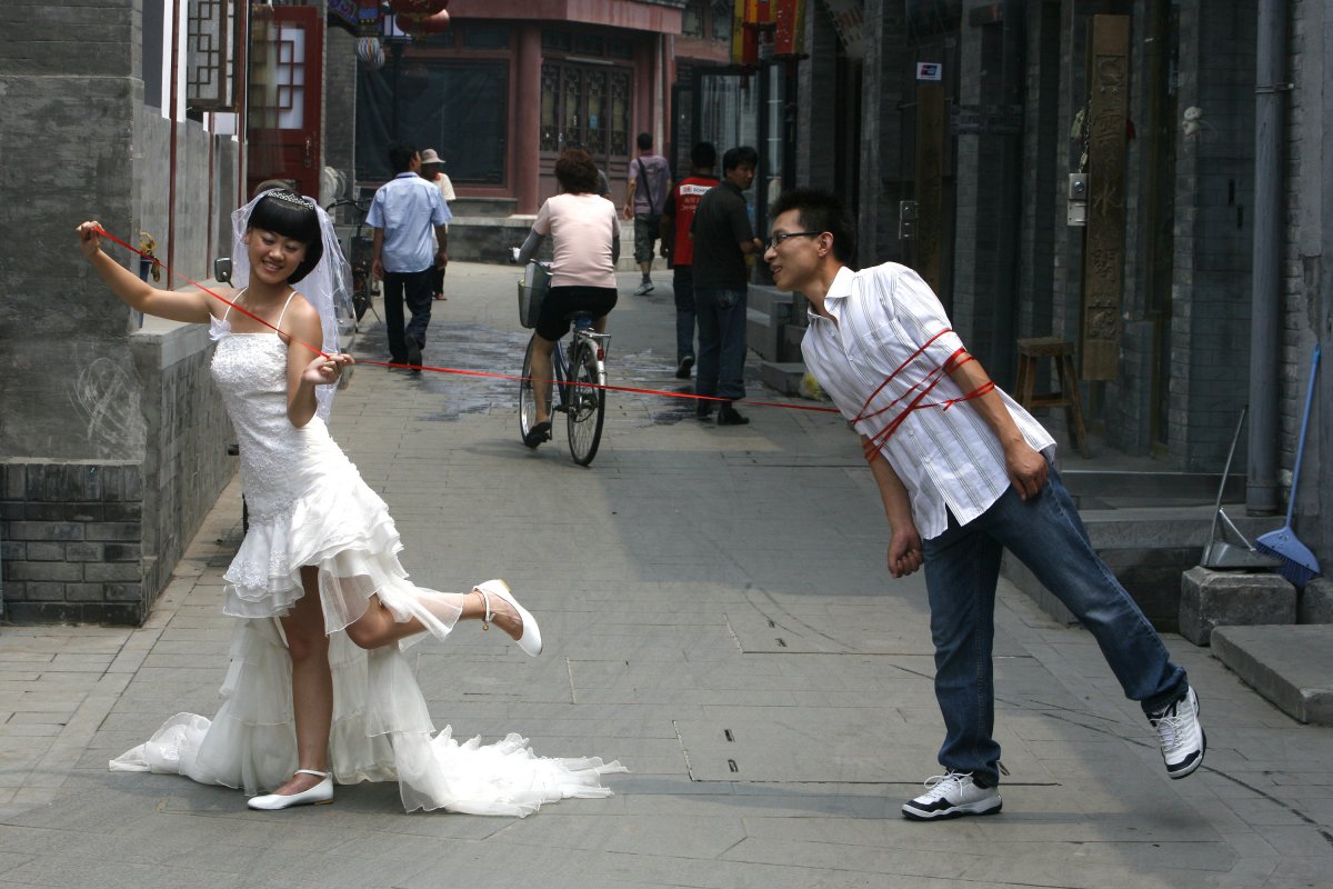 a-chinese-couple-poses-for-a-wedding-photo-on-a-busy-alleyway-or-hutong-in-beijing