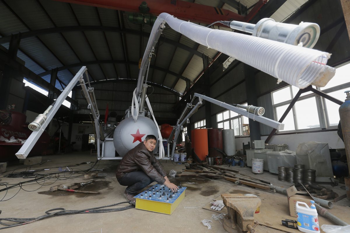 zhang-wuyi-looks-up-as-he-squats-under-a-suction-pipe-of-his-new-submarine-that-captures-sea-cucumbers-at-his-workshop-in-wuhan-hubei-province-march-25-2013