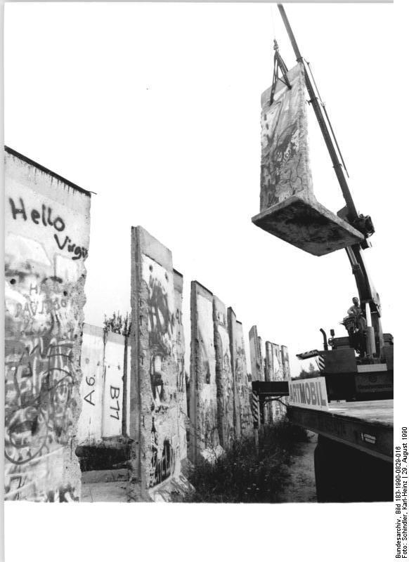 ADN-Karl-Heinz Schindler-29.8.90-Berlin: Ein Stück Berliner Mauer für die Kennedys- Das Segment der Berliner Mauer, ordentlich mit der Nummer A 8 katalogisiert, schwebt vom Lagerplatz der NVA bei Bernau. Es wird nach Übersee verschifft werden. Empfänger ist die Schwester des ehemaligen US-Präsidenten John F. Kennedy, Jean Smith-Kennedy. Ihr wird das 2,6 Tonnen schwere und 3,60 Meter hohe sowie 1,20 Meter breite Stück der "Berlin wall" als Spende für die John-F.-Kennedy-Bibliothek in Boston überlassen.