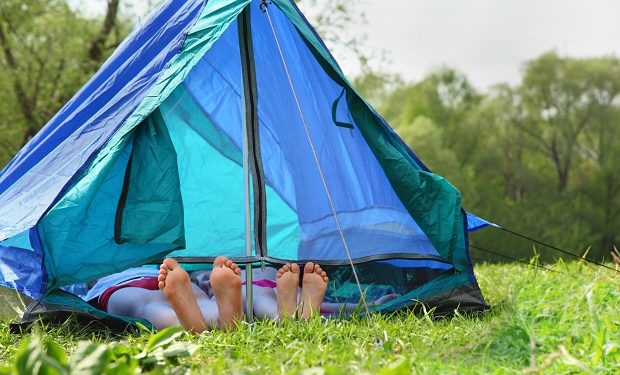 Two pairs of legs stick out from tent on meadow