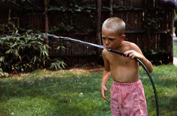 ca. 1950-1965 --- Boy Drinking Water from Garden Hose --- Image by © William Gottlieb/CORBIS