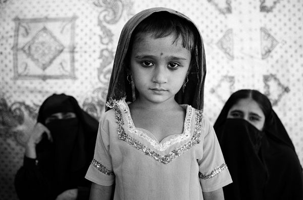A young girl poses while her mother waits to see a doctor in a tent camp for flood victims. Sukkur, Pakistan, 2010
