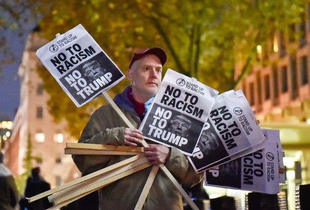 A-man-holds-placards-at-an-anti-racism-protest-against-US-President-elect-Donald-Trump-outside-of