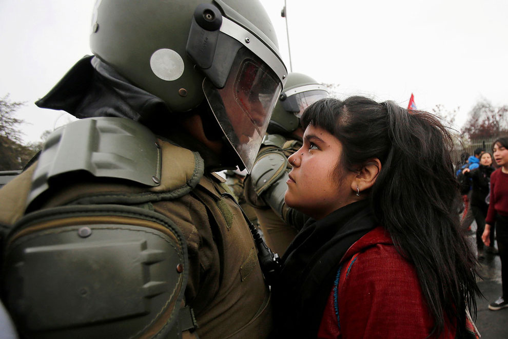 A demonstrator looks at a riot policeman during a protest marking the country’s 1973 military coup in Santiago, Chile September 11, 2016.