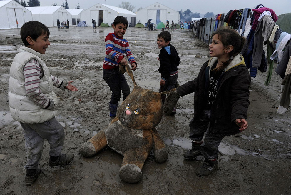 Refugee children play with a stuffed toy at a muddy makeshift camp at the Greek-Macedonian border, near the village of Idomeni, Greece March 15, 2016.