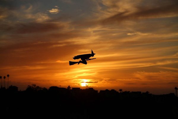 a-remote-controlled-plane-in-the-form-of-a-witch-flies-over-a-neighborhood-as-the-sun-sets-during-halloween-in-encinitas-california