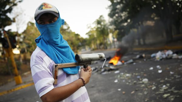 A demonstrator stands guard with a rudimentary mortar in front of a burning barricade during protests against Nicolas Maduro's government in San Cristobal, about 410 miles (660 km) southwest of Caracas, February 26, 2014. Pope Francis called on Wednesday for an end to violence in Venezuela that has killed at least 13 people and urged politicians to take the lead in calming the nation's worst unrest for a decade. REUTERS/Carlos Garcia Rawlins (VENEZUELA - Tags: POLITICS CIVIL UNREST) - RTR3FRE0