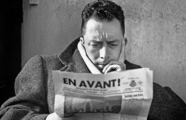 Albert Camus (1913-1960) journaliste redacteur en chef du journal Combat de 1944 a 1947 ici lisant le journal "En Avant !" journal de l'Armee du Salut au cafe Les Deux Magots a Paris en 1945 --- Albert Camus (1913-1960) french writer here writing a paper in 1945