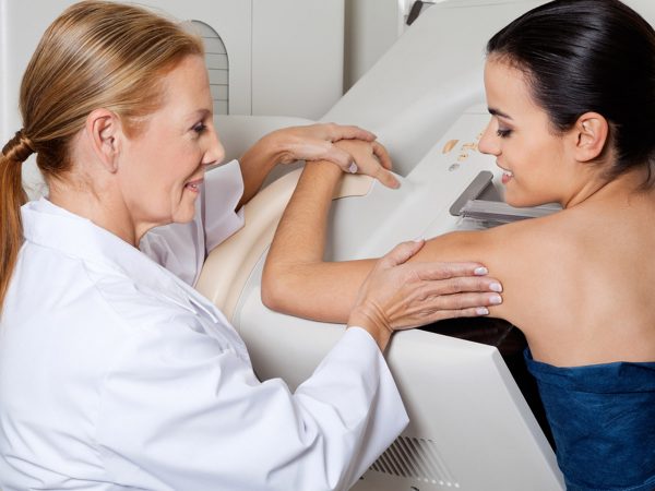 Mature female doctor assisting young patient during mammography; Shutterstock ID 123448411; PO: dicembre