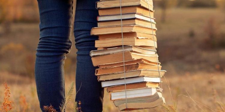 Hipster girl holding a stack of books