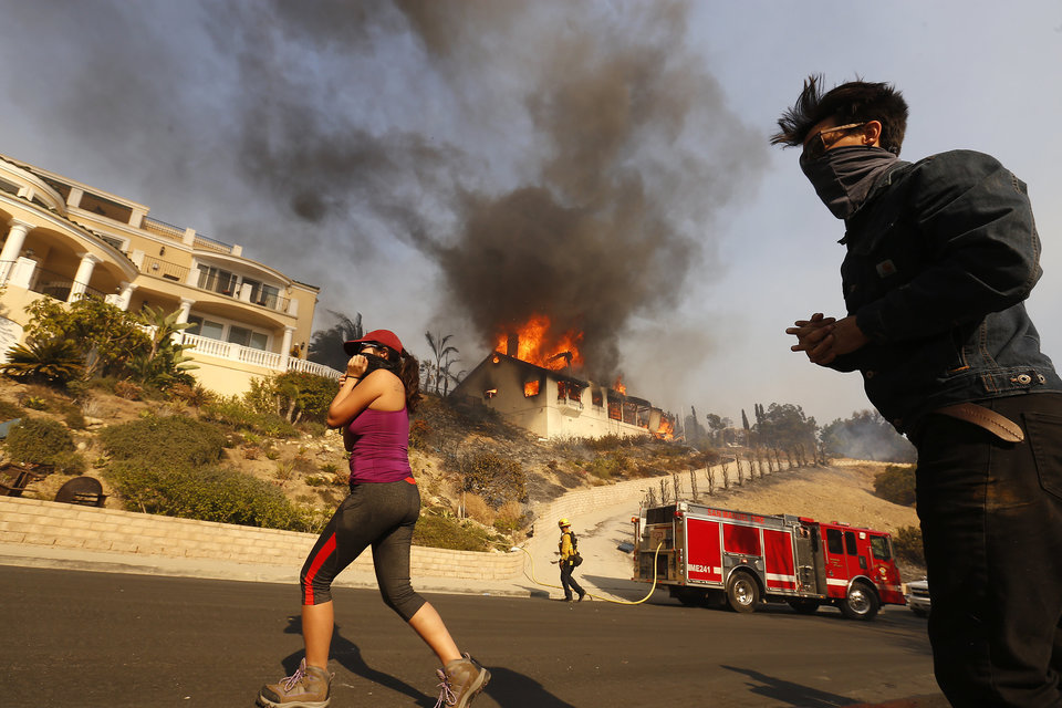 VENTURA, CA - DECEMBER 05: Amanda Leon and husband Johnny Leon watch as Firefighters fight to save multi-million dollar homes along Cobblestone Drive near Foothill Road and North Victoria Avenue Tuesday midday after a fast-moving, wind-fueled wildfire swept into Ventura destroying many homes early Tuesday, burning over 45,000 acres, destroying homes and forcing 27,000 people to evacuate. (Photo by Al Seib/Los Angeles Times via Getty Images)