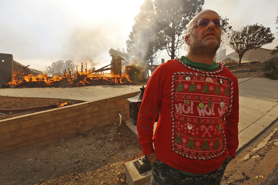 VENTURA, CA - DECEMBER 05: Wearing his Christmas garb Justin Ekback watches as Firefighters fight to save multi-million dollar homes along Cobblestone Drive near Foothill Road and North Victoria Avenue Tuesday midday after a fast-moving, wind-fueled wildfire swept into Ventura destroying many homes early Tuesday, burning over 45,000 acres, destroying homes and forcing 27,000 people to evacuate. (Photo by Al Seib/Los Angeles Times via Getty Images)