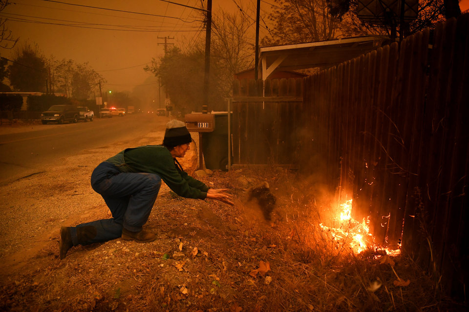 VENTURA, CA - DECEMBER 5: Carolyn Potter tries to save her house as she throws dirt on her fence along Nye Road Thomas Fire in Casita Springs in Ventura County Tuesday. (Photo by Wally Skalij/Los Angeles Times via Getty Images)